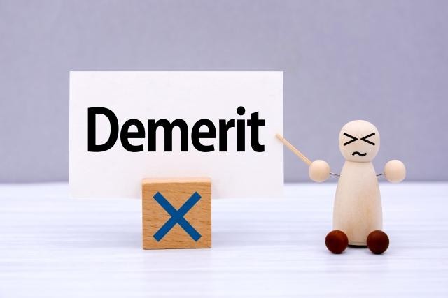 デメリットの文字を指さす人形