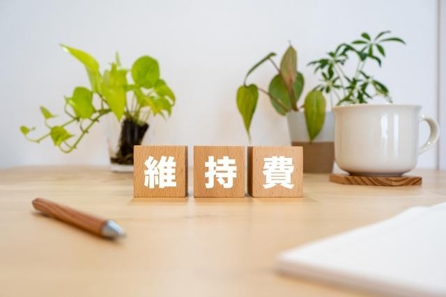 維持費の文字と植物・カップ・ペン
